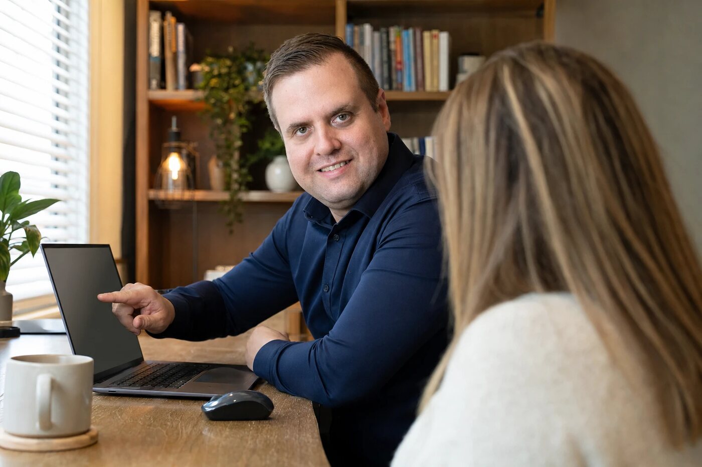Afford IT technician pointing out something on a laptop screen to a client